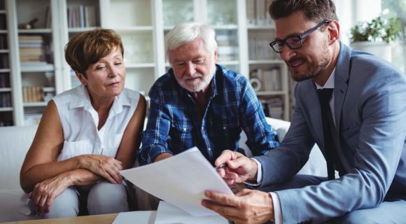 an older couple asking questions to a man holding a piece of paper