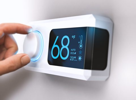 hand turning down temperature for home energy savings