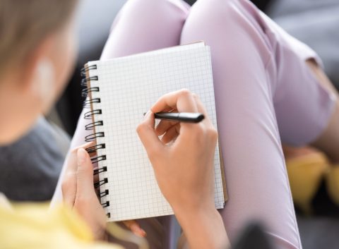 selective focus of woman writing in empty textbook