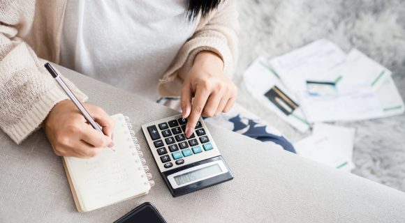Woman looking at finances with calculator and notepad