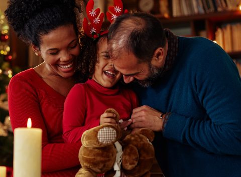 niño sonriente con sus padres con decoración navideña de fondo