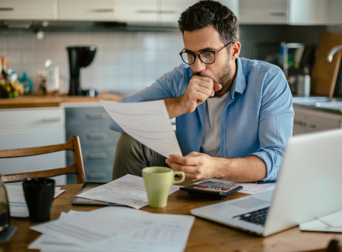 man looking at past due bills at table
