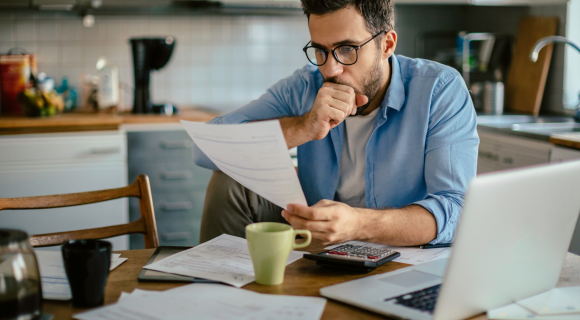 man looking at past due bills at table