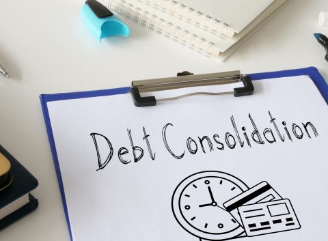 Clipboard with paper labeled “Debt Consolidation” and illustrations of a clock and credit cards, surrounded by office supplies.