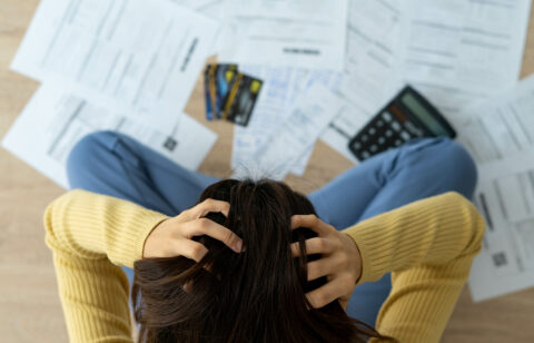 frustrated person looking at bills and credit cards