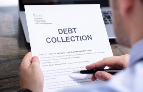 Person holding a debt collection letter while reviewing its contents with a pen in hand.