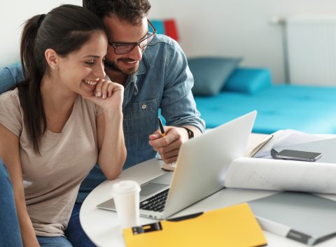 Smiling couple working on financial planning or budgeting together on a laptop.