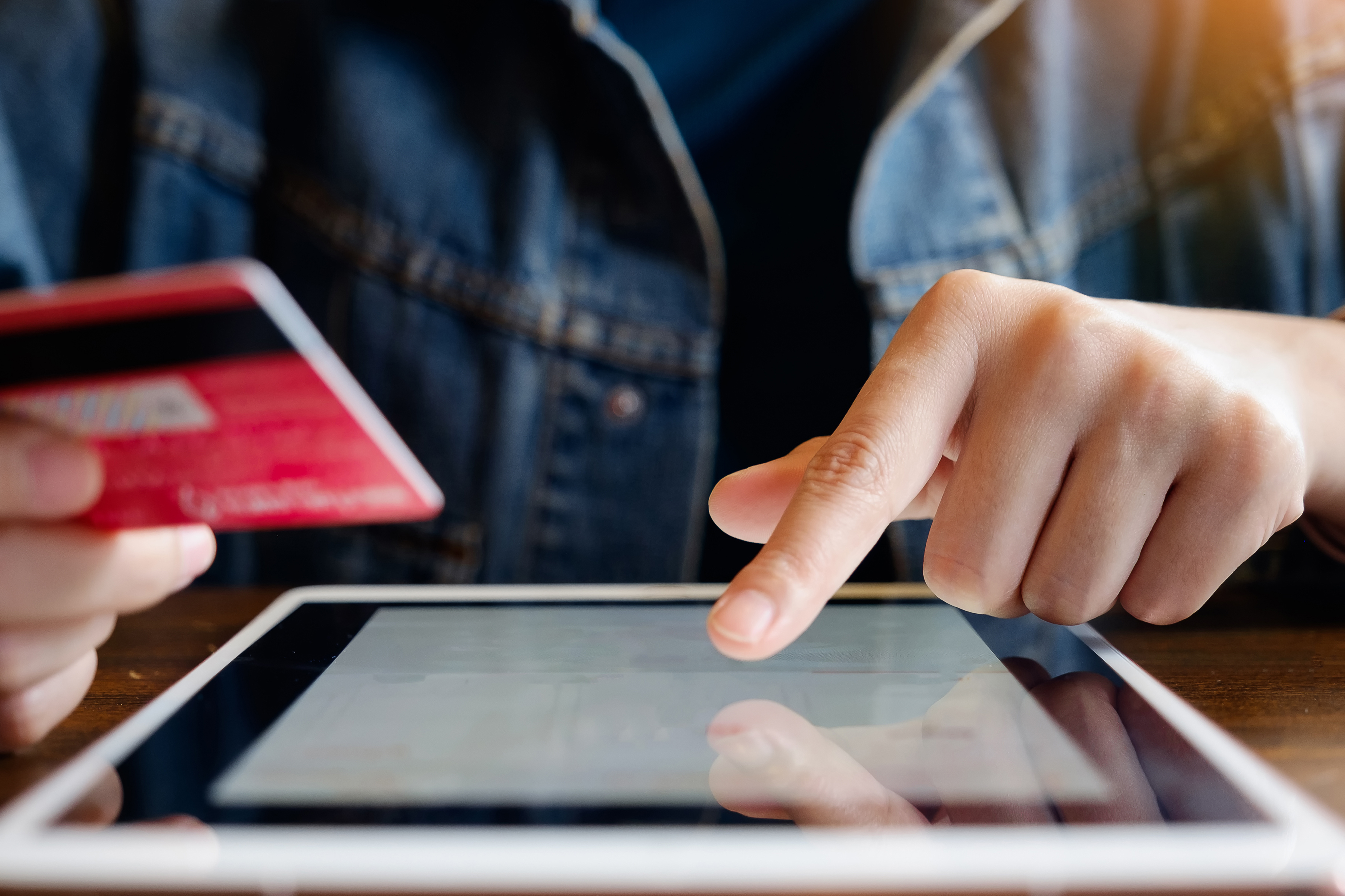 person holding credit card and typing on tablet