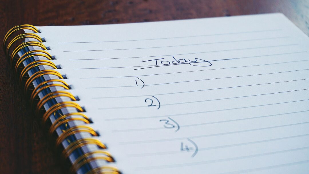 Close-up of a spiral notebook with a handwritten to-do list titled 'Today' and numbered tasks.