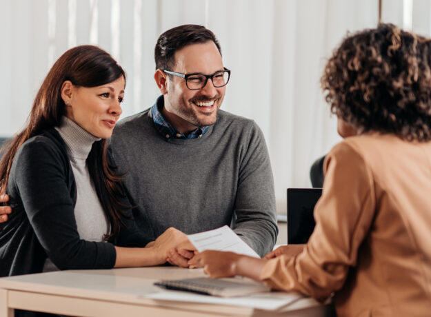 Smiling couple meeting with a professional advisor at a desk