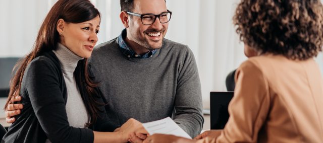 Smiling couple meeting with a professional advisor at a desk