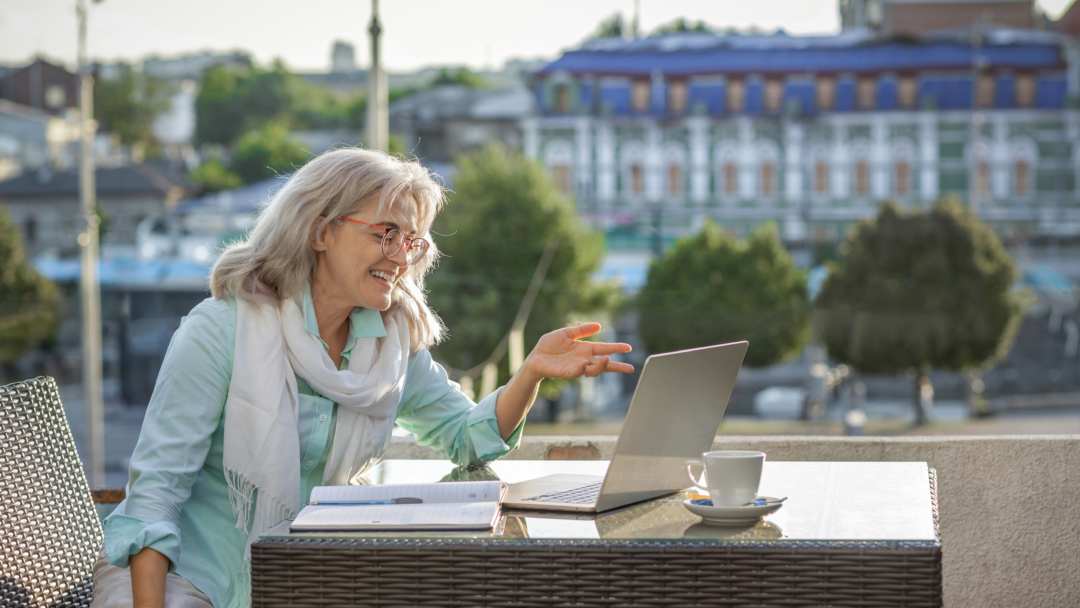 Person sitting on a couch holding an open, empty wallet, surrounded by bills, a calculator, and a laptop on a table.