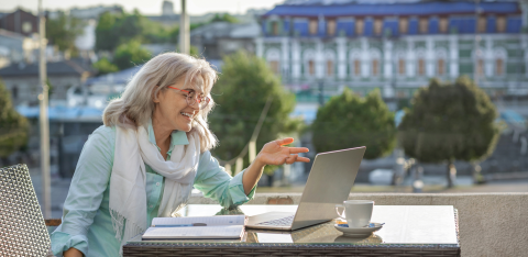 Person sitting on a couch holding an open, empty wallet, surrounded by bills, a calculator, and a laptop on a table.