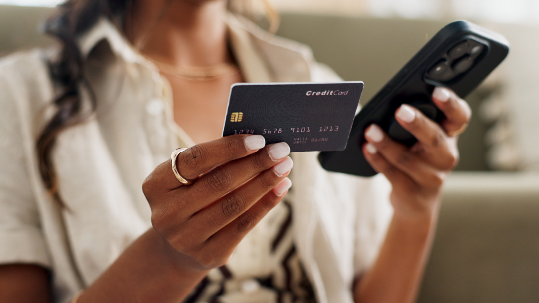 Woman holding a credit card in one hand and a smartphone in the other