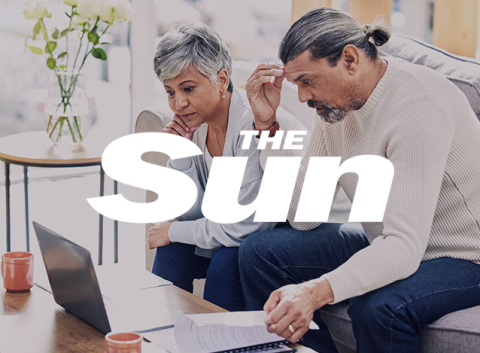 Older couple sitting on a couch reviewing documents and a laptop, with The Sun logo overlayed.